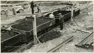 A photograph of two men inspecting a coal mine train.