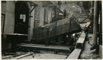 A photograph of a man either loading or unloading a large piece of cargo next to a warehouse. 'D.L. Scott'