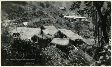 A photograph of thatched huts on a hillside. 'D.L. Scott'