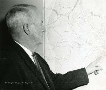 A photograph of G. Cliff Hough examining a map of the Morgantown area.
