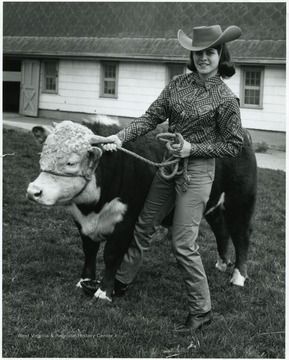 A photograph of Charlene Jamison posing with a cow.