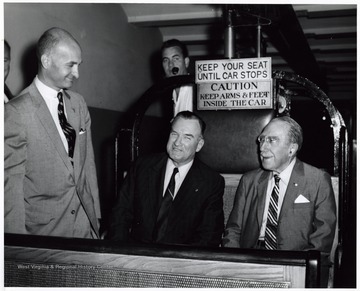 A photograph of Senator John D. Hoblitzell, Jr. (left) speaking with Senator Theodore Green (R.I.; seated right) and another man as they sit in an open cable car.