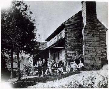 'The scene of the Indian massacre, led by Tecumseh, the famous Shawnee Chief in 1792 in which all the family were either killed or taken captive, but one. Places for the use of a rifle can be seen near the roof or house near the chimney.; Front row (seated): Alvin Waggoner and brother, John, Alvin's wife and two children. Second row: George Waggoner and wife and father, Uncle Elijah Waggoner.'