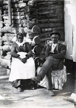 A photograph of two African Americans sitting outside their home.