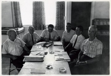 A photograph of a group of men sitting around a table.