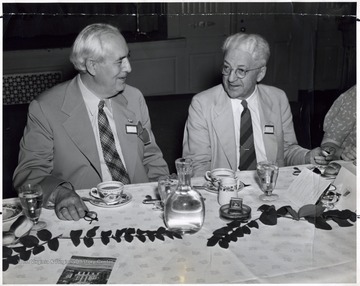A photograph of Lorren Johnson (left) and J. W. Wooddell (right) seated at a dinner table.