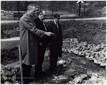 A photograph of Dr. Wiles (center), County Health Agent, with others inspecting a gravel pit.