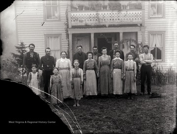 A portrait of extended family; the photo is taken outside of the house.