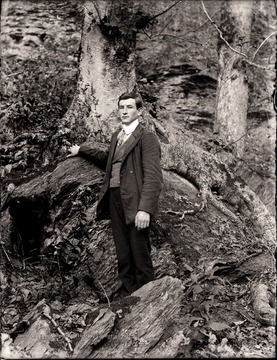 A man standing near a boulder.