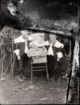 A portrait of two boys and an infant in high chair.