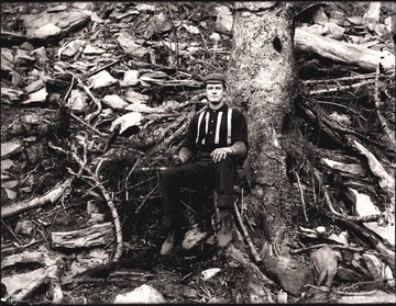A portrait of man sitting at the bottom of tree.