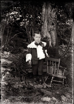 A portrait of Herbert Shock next to chair taken outdoor at the bottom of the tree, Helvetia, W. Va.