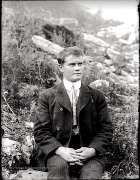 A portrait of man sitting on a hillside.