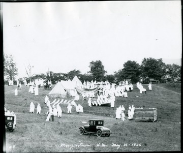 Ku Klux Klan members setting up tents and raising flags for meeting.