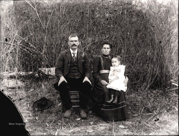 A portrait of a couple and girl sitting on woman's lap.