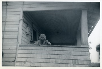 May Moore is looking down from a front porch.