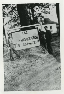 Three men in front of sign that reads C.C.C Camp Rhododendron S-75 Company 3527. Names Deb; Joe; and Goob appear on back of photo.