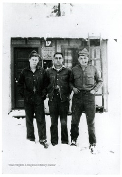 Three camp friends stand in the snow in front of Unit 17.