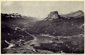 "Looking West down Bow Valley, with Mount Temple on the left and Castle Mountain on the right, the Canadian Pacific Railway can be seen threading its way through the valley to the Pacific.'