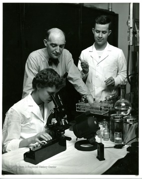 Students of Medical Technology examine specimen in the lab while a professor watches them over.