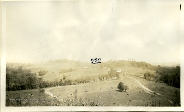 'East of Boaz.  The 960 level is at the ridgepole of the house, as marked.  Three rock benches are noticeable in the picture: one is near the top of the hill in the right center, one is at the level of the house that is marked, and one is in the field this side of the barn and house.  The roads in the foreground are on fine material weathered from the shale.'