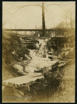 Near the WVU campus, the walkway bridge over Falling Run Hollow, connecting the campus to Sunnyside, can be seen in the background. The photograph was taken before the stadium was built.