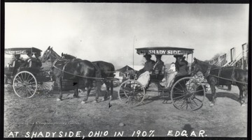 Several unidentified folks sit in a line of "surreys" or  two seated horse-drawn buggies.