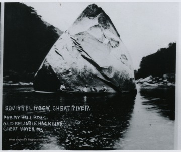 Unidentified group pose in their canoe in front of the rock.