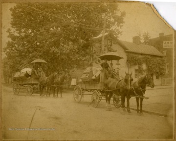 ' "Wood's house" of two horse drawn wagons, each pulling a man, a boy and furniture on Pleasant Street and University Ave in Morgantown, W. Va.