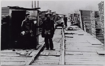 Two man standing on the dock of a lumber yard. Thought to be Mayton Lumber Co., Hacker Valley, W. Va. 