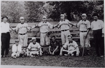 Team posed with baseball gloves, bats, and umpire gear.