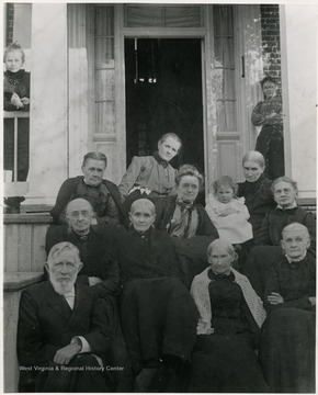 On the back: "Man seated nearest bottom of stairs- the Rev. George White. Woman seated just above- Mrs. M. W. Gamble I. Woman seated just above Mrs. M. W. Gamble I- Mrs. J. J. Gilkeson. Woman seated directly behind baby- Nannie Bell McNeill. Baby- Carrie Gilkeson Breathed."  Taken before new porch was built on Presbyterian House.  