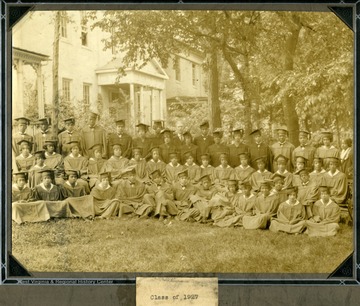 Group shot of students in caps and gowns sitting on the Storer College lawn.