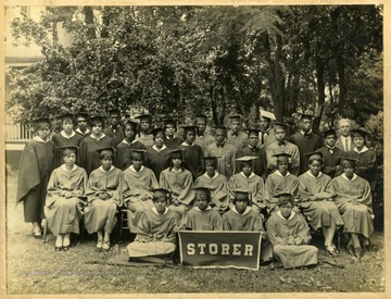 Storer College class of 1929 in caps and gowns on law of campus. First Row: Finely-(?, Moore,-Edwards. Second Row: Coleman, Heath, Stevens, Johnson, Holland, Morris, Dixon, Bibby. Standing: Spencer, Harris, Brown, Daily, Johnson, Tall, Heath, Brooks, Brown, Wilson, Hill, Perry, Sims, Johnson, Pierce, Carroll, Thomas, Washington, Pres. McDonald. Jackson.