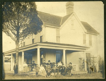 "Which was built on site of original log home. E. Emil Madera- leaning against the famous pine tree. Mrs. Gertrude Hare- (Dunbar P.C.) Mr. H.G. Madera- with Bruce dog. Mrs. Nora Madera. Grandfather Andrew Jackson Koontz. Grandmother Mary Catharine Koontz. Mrs. Ella Barnetta (Lemont Furnace Pa.) Front: George Washington Koontz, Ms. Ida F. Koontz, Chas Koontz, Omer H. Koontz, Charles W. Koontz, James A Koontz, Calvin W. Smith, Shep-dog."