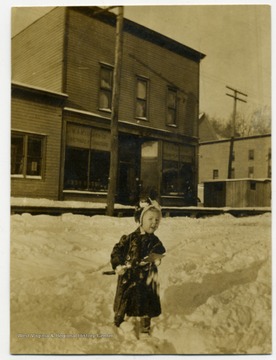 A little boy plays in the snow on the town's main road street.