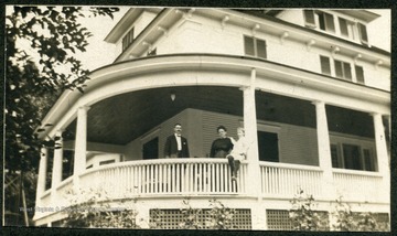 Man, woman, and child on the wrap around porch of the J. Hammond Siler house.