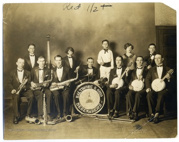 Group portrait of musicians holding their instruments including banjos, saxophones, trumpet, trombone, drum set, upright bass, and violin.