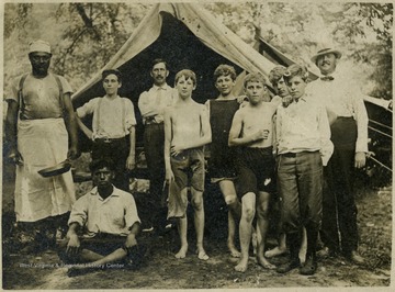 Several boys and three men in front of tent at "J. A. de Gneyter's Camp"