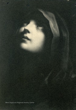 Portrait of a hooded young woman gazing up to the left.