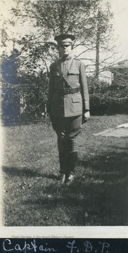"Captain" Frances D. Packette standing "at attention" dressed in an army uniform. This is a staged photograph, women were not permitted to serve in the military. 