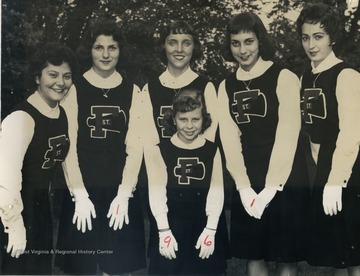 Group portrait of unidentified members of the St. Francis Cheerleaders in uniforms including white gloves.
