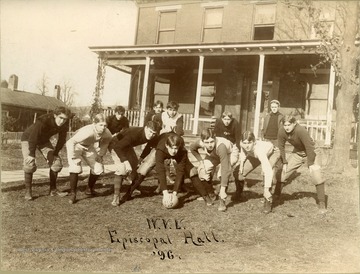 Students in football uniforms pose in offensive set in front of Episcopal Hall.