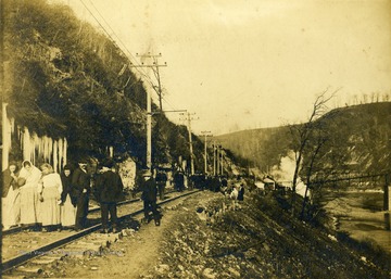 In Monongah, West Virginia, December 6, 1907, an explosion destroyed Mines #6 and #8, killing most of the miners inside. The women in the foreground of the photograph, along with other families walked back and forth on the railroad tracks from one mine entrance to the other searching for news of loved ones. An eyewitness reports many women walked for more than 20 hours without food or sleep and some "were about to become mothers". The official death toll was 361 mine workers killed.