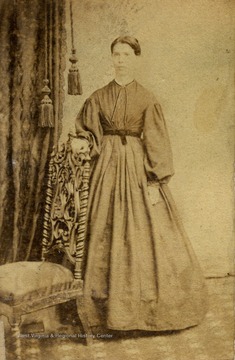 The young woman is wearing a dress with garibaldi sleeves, a popular fashion in the mid 1860s. Her a hair is also styled in the fashion of that period.