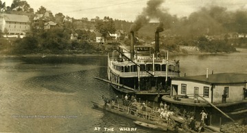 Postcard photograph of the steamboat, "Columbia" on the Monongahela River, pulling up to a towboat and the free ferry already loaded with wagons and a buggy. See the original for the correspondence written on the back.