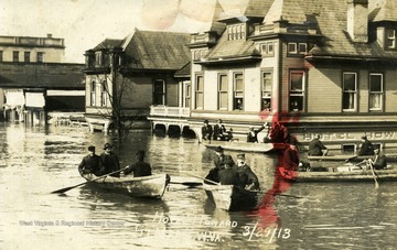 Postcard photograph of the Hotel Howard half submerged in flood waters and several rowboats being used to navigate through town during a major flood in St. Marys, West Virginia. See the original for the correspondence written on the back.