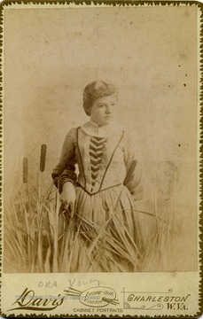 A cabinet card portrait of Ora Young, daughter of J. M. Young, posing among "cattails".