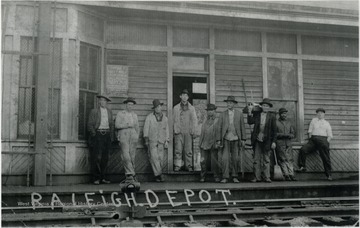 Unidentified workers pose in front of the depot, along an empty track.