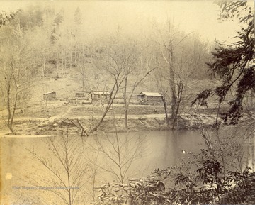 Cabins and structures on the far river bank, occupied by the Norfolk and Western railroad civil engineers during the construction of the Ohio extension.